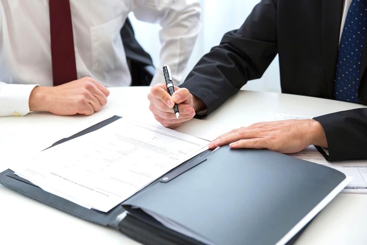Two businessmen in a meeting. One is signing a document.