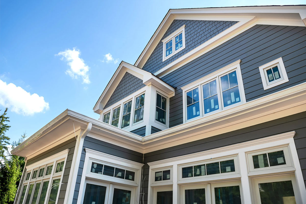 A large house with blue siding and white trim. The house has many windows.