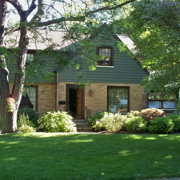 A charming two-story house with a well-manicured lawn. The house features a combination of brick and siding exterior.